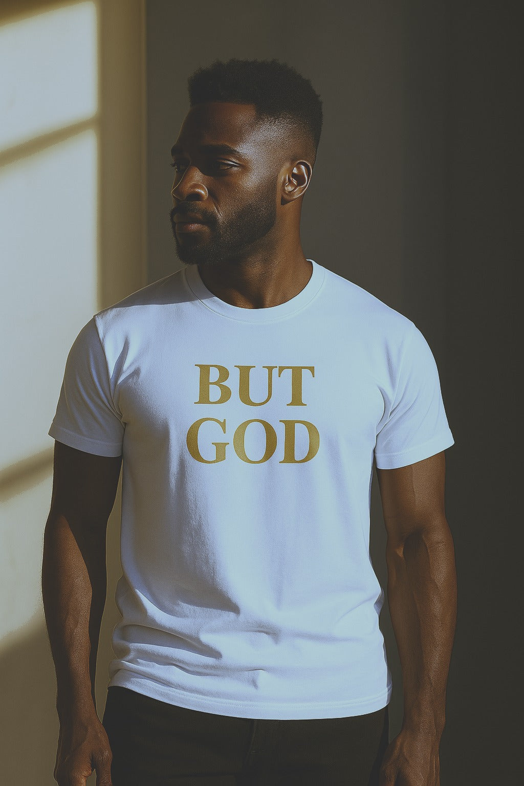 Man wearing white “BUT GOD” Christian t-shirt with metallic gold print against a sunlit wall
